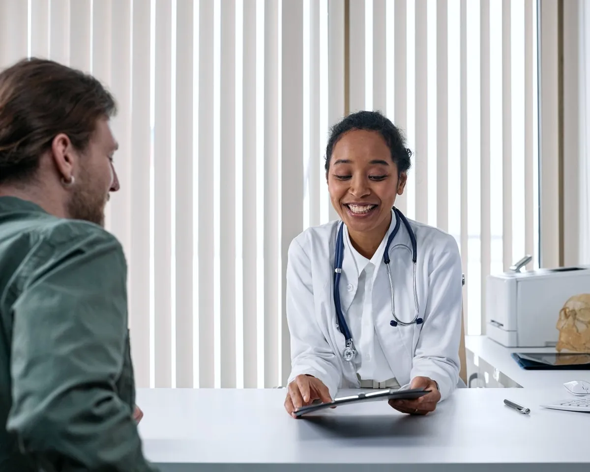A doctor talking through results with a patient across her desk